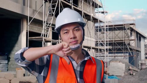 Asian Male Engineer Showing Thumbs Down Gesture And Shaking His Head At Building Site