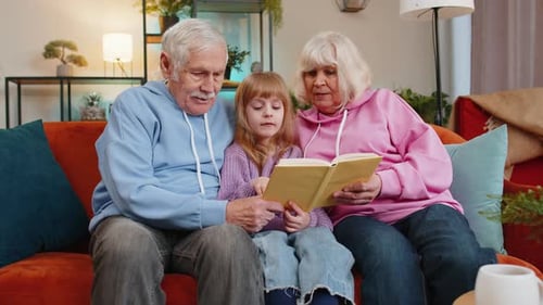 Grandparents Reading Book with Grandchild on Couch