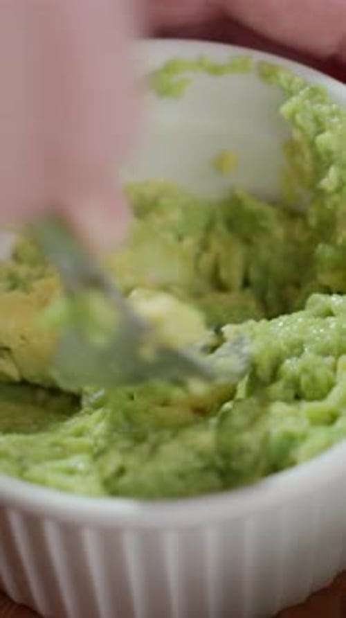 Mashing Avocado in White Bowl with Fork