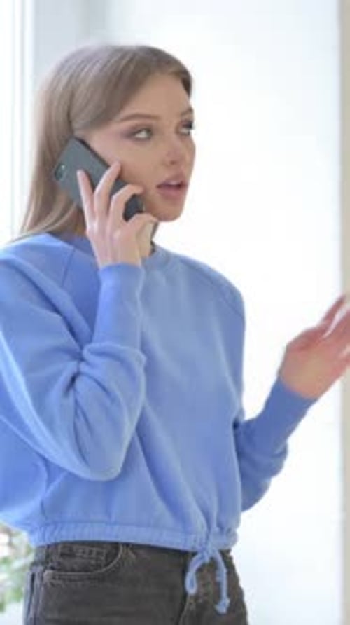 Attractive Woman Talks on Phone Indoors Near Window