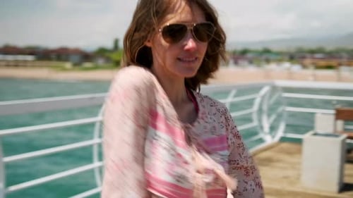 Sexy woman dancing shaking head on pier on summer vacation near the beach enjoying the seascape