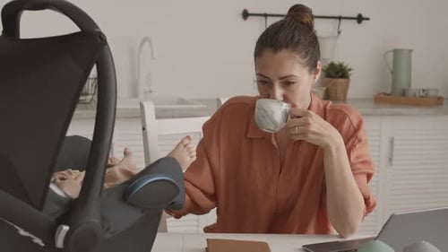 Young female stand near apartment window and enjoy morning coffee in sunlight
