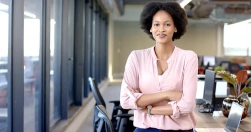 African american woman standing confidently with arms crossed in modern office