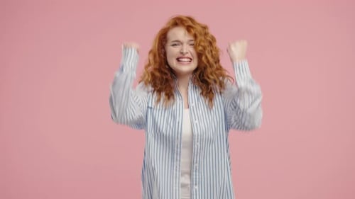 Excited Woman Cheering and Pumping Fists on Pink Background