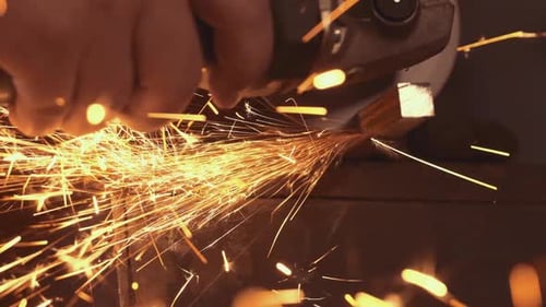 Worker Cutting Metal with Angle Grinder Creating Sparks