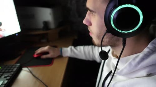 Young Adult Gaming with Headphones in Dark Room