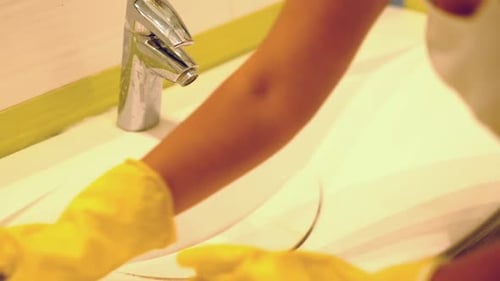 Mujer a cámara lenta haciendo tareas en el baño de su casa limpiando el lavabo y el grifo con detergente en aerosol
