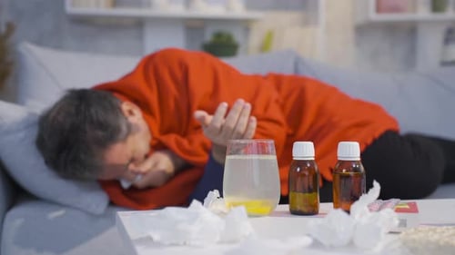 Sick Adult Man on Couch with Medicines