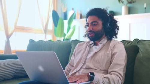 Man Using Laptop and Headphones on Couch