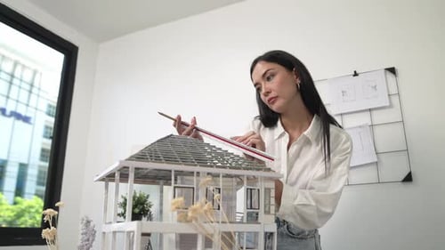 Professional architect using ruler measuring model roof length. Immaculate.