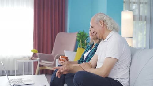 Adults Watching Laptop Together on Cozy Sofa