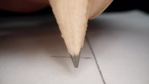 Close-up of a pencil held by a hand writing something on paper. POV.