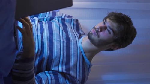 Teenager using laptop in bed, sleepless and tired.