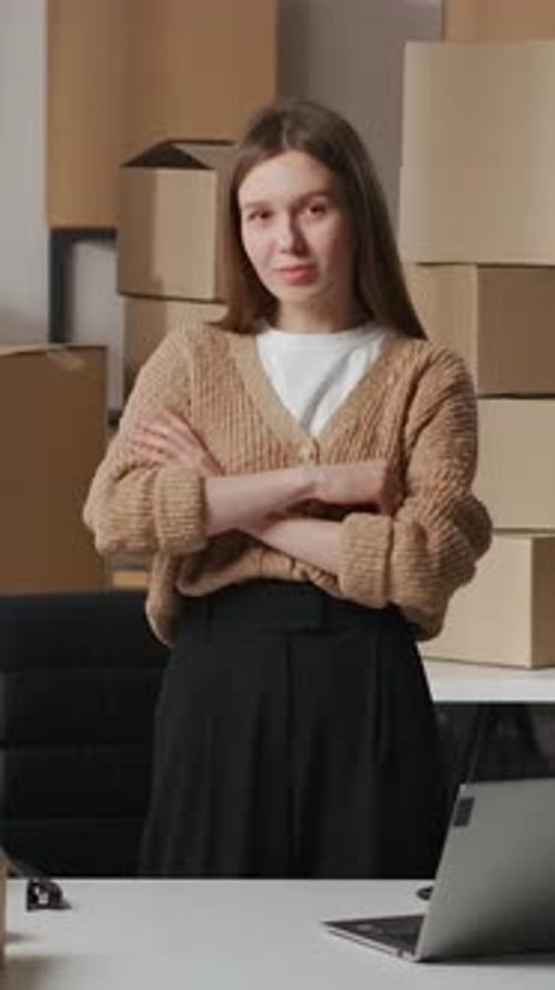 Confident Woman Stands at Desk with Boxes Behind