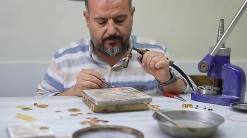 Juwelier arbeitet an einer Bank mit Fackel in der Werkstatt