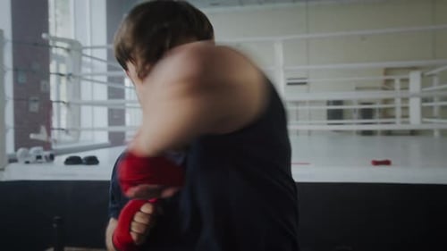 Bearded Man Punching Wearing Red Wraps in Boxing Ring