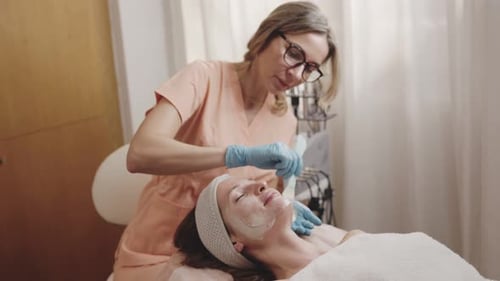 Professional Beautician Applying Facial Mask at Spa Salon
