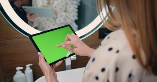 Mujer sostiene un ordenador portátil con una pantalla Chromakey verde en sus manos.