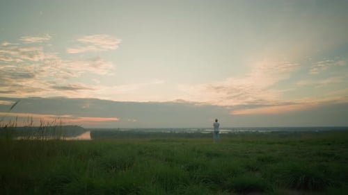 Contemplative Man Standing By a Tranquil Lake at Sunset in a Serene Landscape