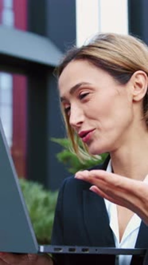 Smiling Woman Video Conferencing with Laptop Outdoors