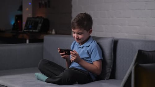 Boy Playing Phone on Couch Indoors