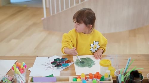 Little Girl Painting Pictures at Wooden Table