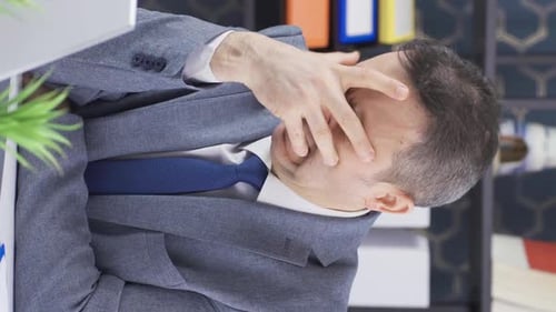 Man Rubbing Face in Stressful Office Scene