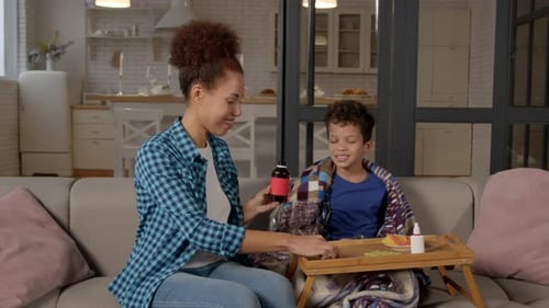 Fürsorgliche afroamerikanische Mutter gibt kranken Sohn im Teenageralter Hustensaft