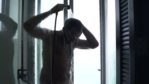 Man Rinsing Hair in Steamy Glass Shower