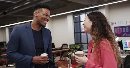 Two happy diverse creative colleagues in discussion in casual office, slow motion
