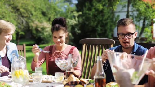 Friends Eating Meal Together Outdoors on Sunny Day