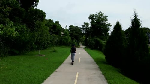 Individualverkehr in der Stadt. Rückansicht eines Mädchens, das Elektroroller auf einem Betonweg im Park Alo fährt