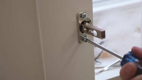 Slow motion close up of a woman screwing a screw into a closet latch of a white wardrobe