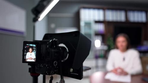 Woman Speaking at Desk Being Filmed