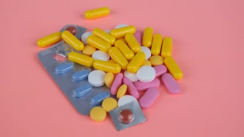 Colorful Pills and Blister Packs on Pink Background