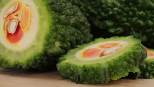 Une gourde amère, un légume souvent utilisé comme ingrédient en cuisine, est posée sur une table en bois.
