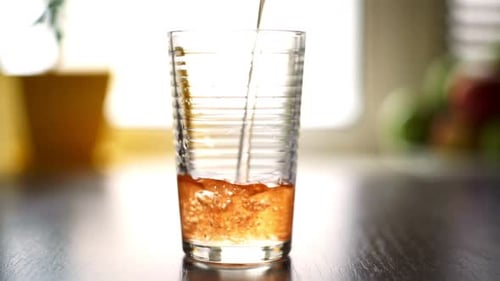 Refreshing orange liquid poured into glass on table