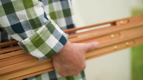 Homme tenant des lattes en bois dans une chemise à carreaux avec fond flou