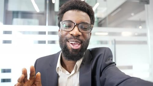 Man Waving During a Video Conference in Office