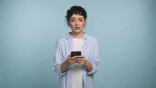 Concerned Woman Using Smartphone Against Blue Background