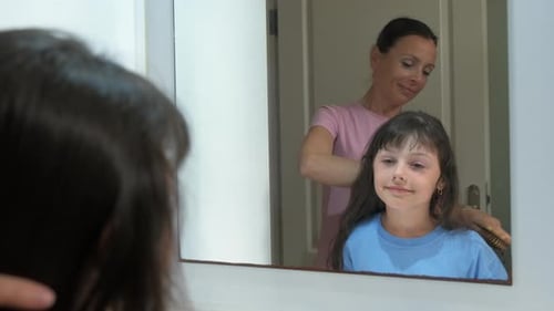 Woman Brushing Little Girl's Hair in Mirror