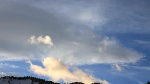 Zeitraffer zeigt Wolken, die sich über einen Abendhimmel bewegen, mit der Silhouette eines Bergrückens. In der