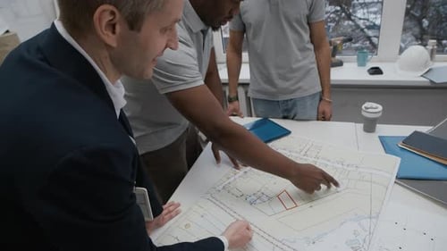 Civil Engineers and Manager Analyzing Blueprint at Office Table