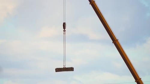 Crane Moves Construction Materials Suspended on Strong Steel Cable