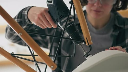 Assembling, A Woman Manually Uses A Working Tool An Electric Drill In A Bright Bright Kitchen