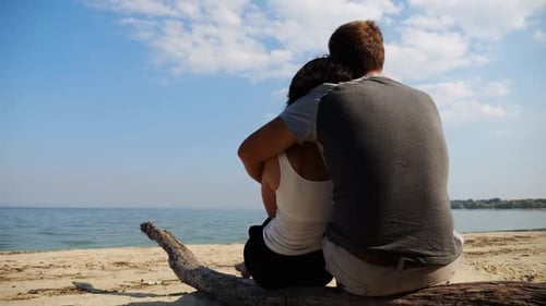 Romantic Couple Hugs During Sitting on Wooden Log on the Beach Happy Pair Admiring a Sea and
