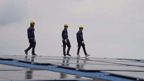 Male engineer team workers walking on the roof of the factory with solar cell installed