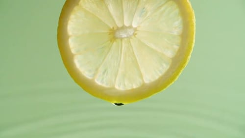 Lemon Slice Drips Fresh Juice Against Green Background