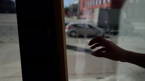 Person Opening a Glass Door with Wooden Handle Seen From Behind with City Street View