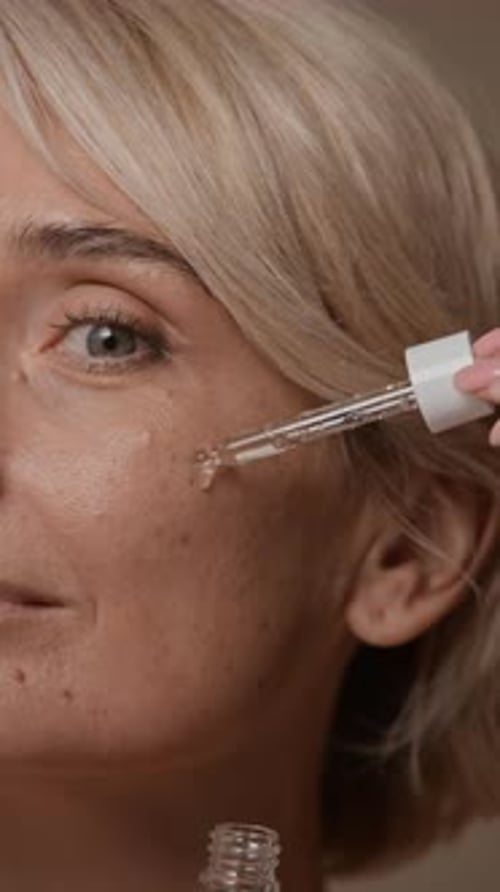 Woman Applying Serum to Face for Beauty Treatment